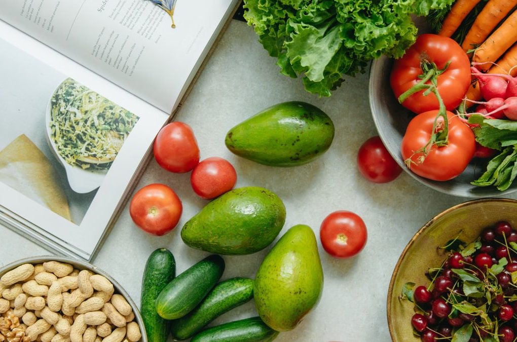 An appetizing display of fresh fruits and vegetables with a cookbook, perfect for healthy recipes.